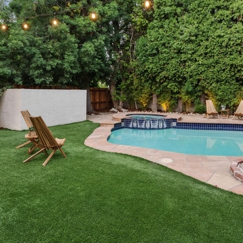 Piscine & Spa de Rêve : Jardin avec Gazon Synthétique Luxueux jardin de soirée : piscine, spa, gazon synthétique et transats en bois. Éclairage suspendu dans la verdure luxuriante.